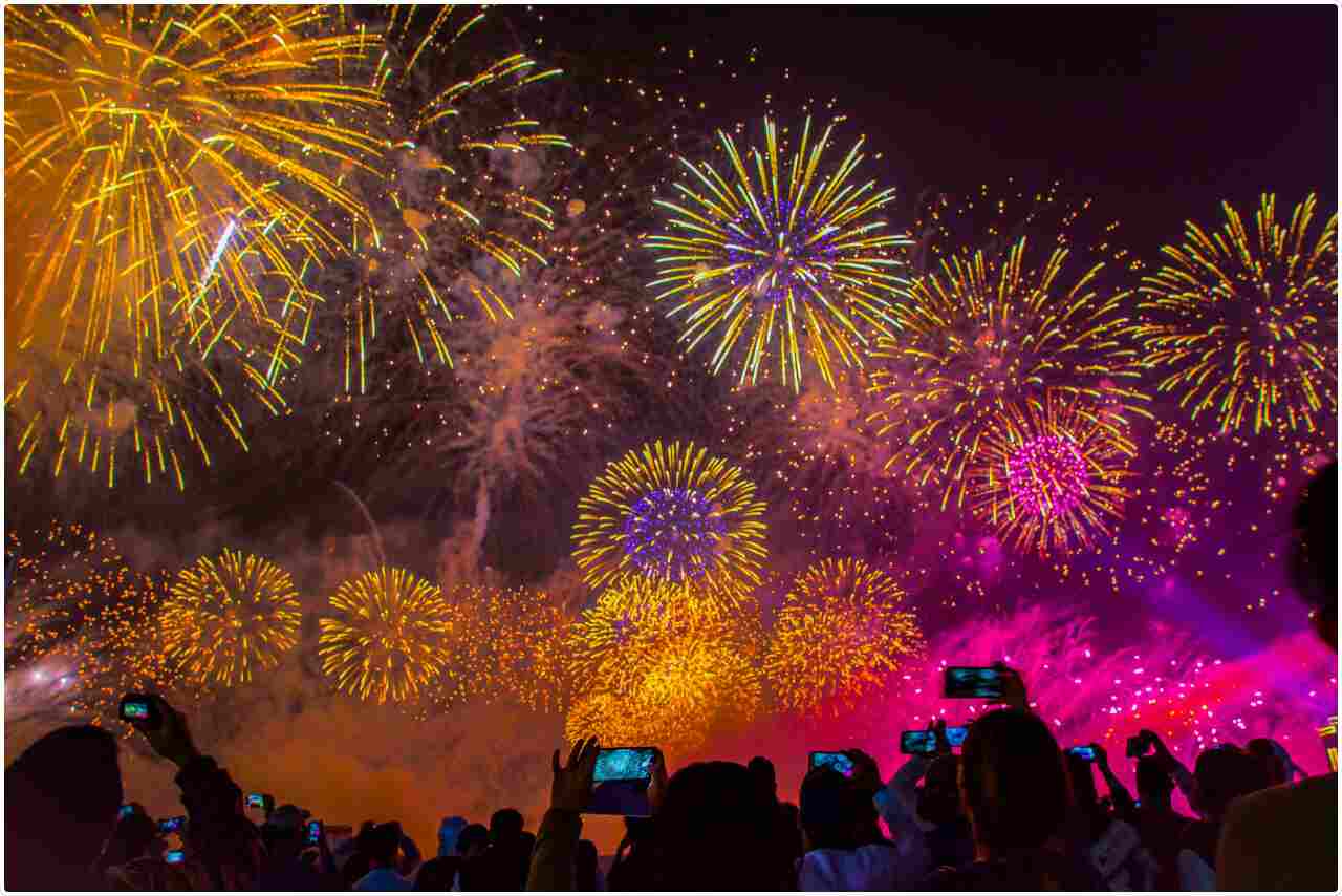 People cheering and capturing moments of a stunning New Year's fireworks show